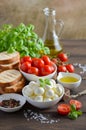 Italian food ingredients Ã¢â¬â mozzarella, tomatoes, basil and olive oil on rustic wooden table. Royalty Free Stock Photo